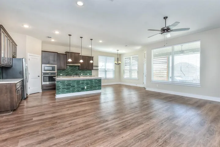 Kitchen featuring light countertops, a center island with sink, open floor plan