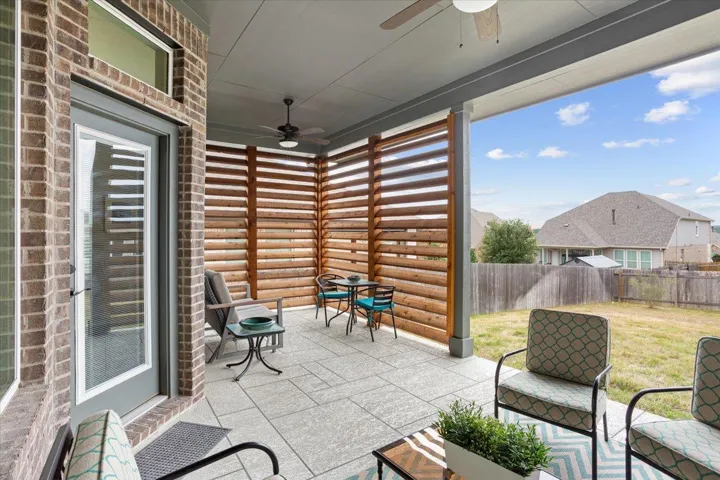 Fenced backyard with ceiling fan and a patio area