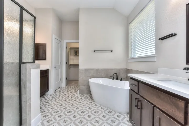 Primary bathroom with a freestanding bath, vanity, a shower stall, tile walls