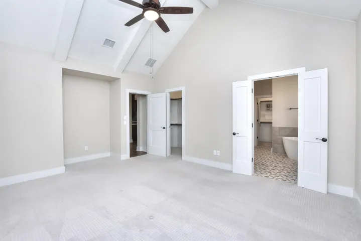 Primary bedroom with vaulted ceilings, and a ceiling fan