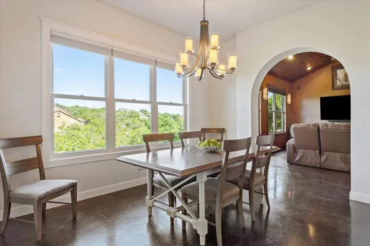 Dining space with archway leading to the flex room. Healthy amount of natural light, a chandelier, & finished concrete flooring.  This light also shines into the kitchen adjoining this area...