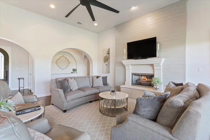Living room featuring ceiling fan, a glass covered fireplace, recessed lighting, and archways for architectural design...