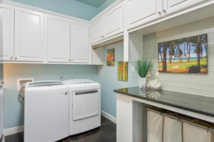 Laundry room with washer and dryer, cabinets, & a black granite folding area with sorting laundry below it...