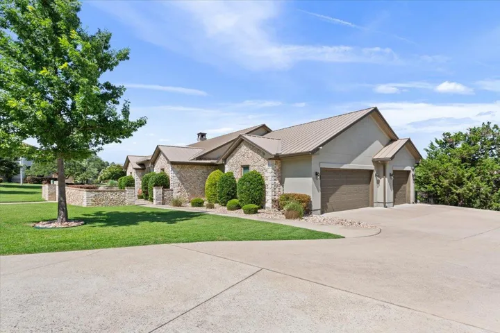 Mid-century inspired home featuring an attached 3 car garage, the front lawn, driveway, metal roof, and stucco siding.  Having company over for dinner?  No problem.  Plenty of space to park!!