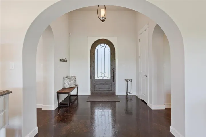 Foyer entrance featuring finished stained concrete flooring and baseboards.  Great front door is metal, wrought iron, and glass...