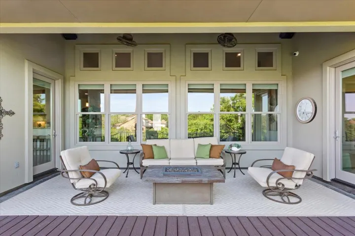 Covered wooden deck with an outdoor living space with a fire pit..