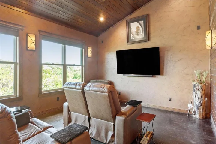 Living room with wooden ceiling, lofted ceiling, baseboards, and finished concrete floors. This room was previously used as "man cave"....is now used as a media room...but it could easily be a large study/office or whatever you need it to be!