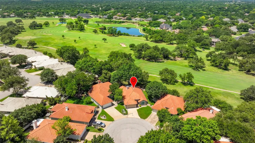 An aerial perspective showcases a vibrant community bordered by a scenic golf course and a tranquil pond.