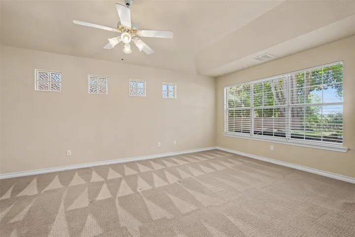 An airy bedroom with a tray ceiling offers a cozy, well-lit sanctuary.