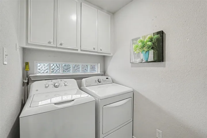 Functional utility room featuring upper cabinetry and a glass block window.