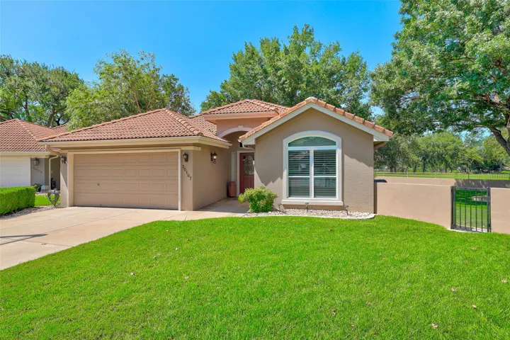 A well-kept yard presents a charming residence with a tile roof and attached garage.