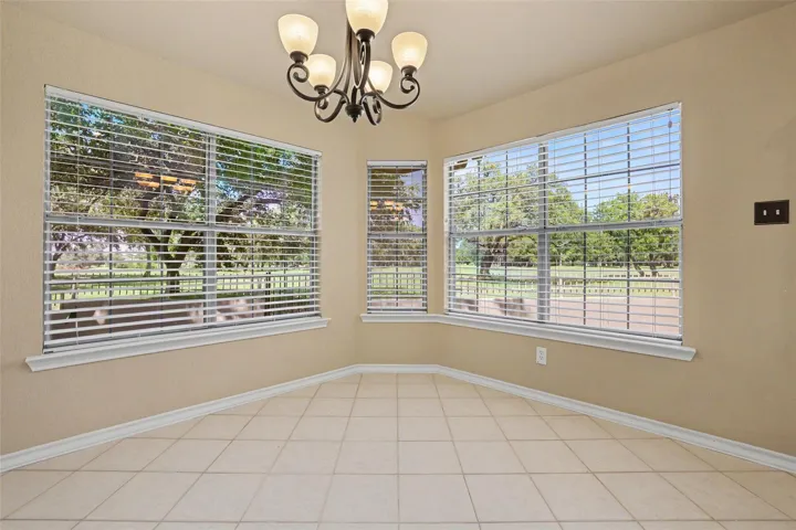 A classic chandelier illuminates this dining space with multiple windows overlooking green grounds.