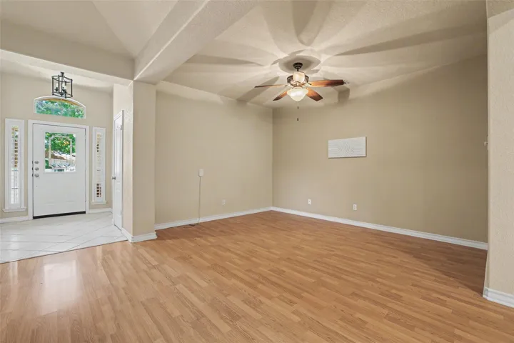 A welcoming entry featuring a decorative transom window, leading to a spacious area with a ceiling fan.