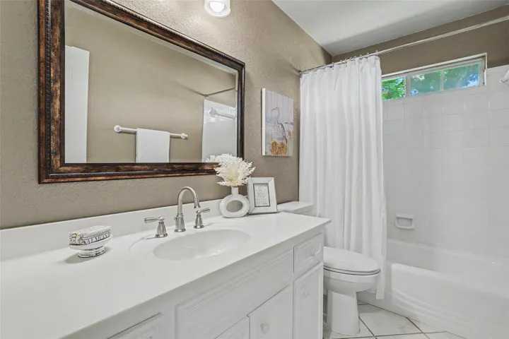 A well-appointed bathroom features a single vanity, a spacious mirror, and a classic tub-shower combination.