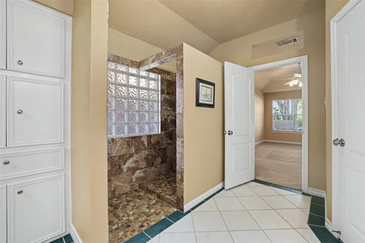 A convenient walk-in shower with natural light connects to a spacious bedroom.