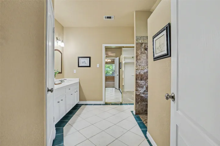 A generously sized bathroom features a dual vanity and a spacious walk-in shower with stone tile.