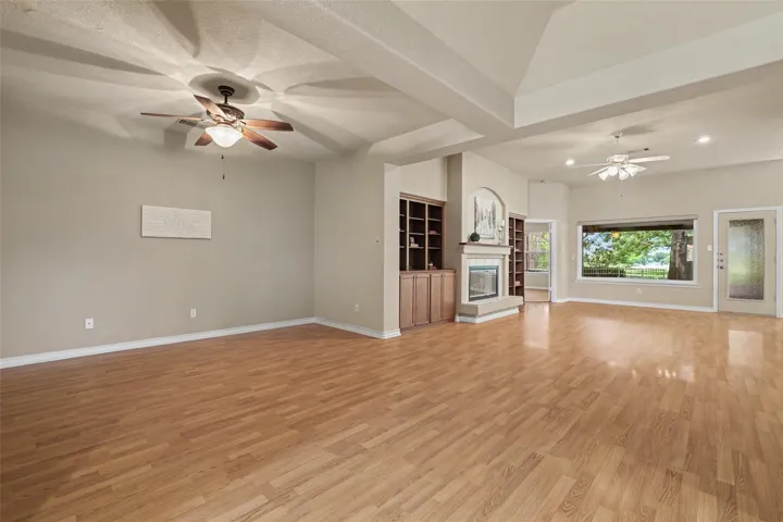 An open floorplan living space offers warm wood floors, built-in shelving, and a cozy fireplace.