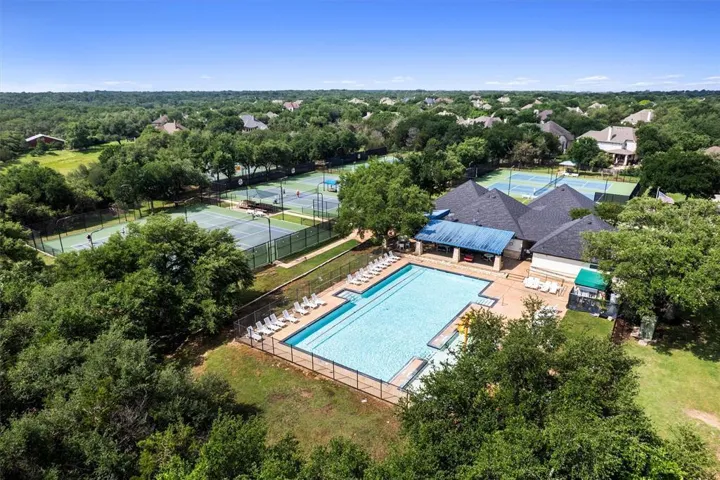 An aerial perspective showcases a vibrant community recreation area with a sparkling pool and multiple tennis courts amidst lush greenery.