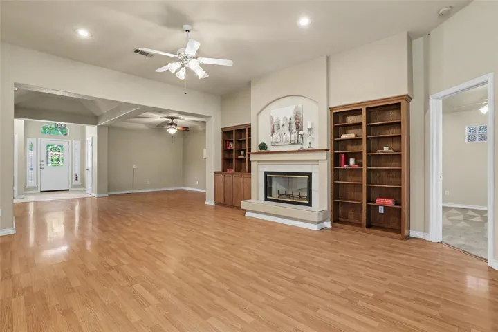 A welcoming entryway flows into a spacious living area featuring built-in shelving and a fireplace.