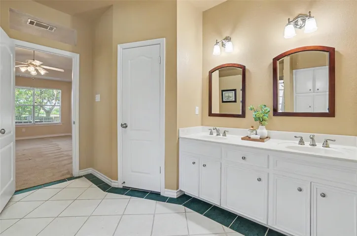 A well-lit primary bathroom vanity provides abundant storage and dual basins.