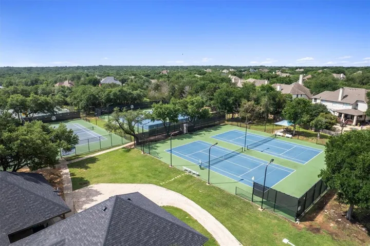 Four tennis courts with clear blue markings invite active play amidst a verdant landscape.