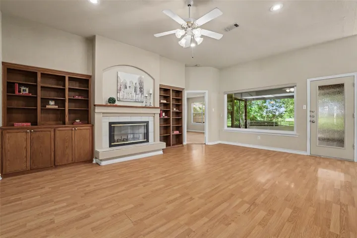 A welcoming living room featuring a cozy fireplace, built-in shelving, and large windows that offer views of the outdoors.