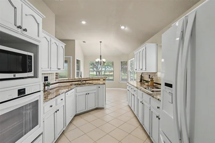 Granite counters and white cabinetry define this bright kitchen, complete with a built-in oven and microwave.
