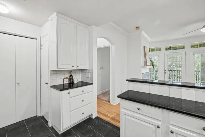 White cabinetry, dark countertops, and modern flooring define this efficient kitchen space.