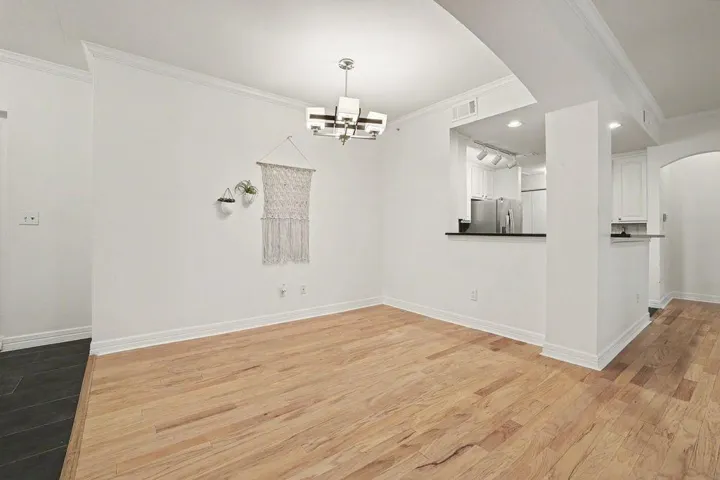 Hardwood floors and a sleek modern chandelier define this welcoming dining area, opening to a well-appointed kitchen.