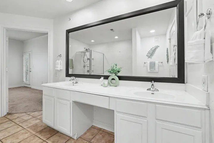 A well-appointed primary bathroom featuring a spacious double vanity and an expansive mirror.