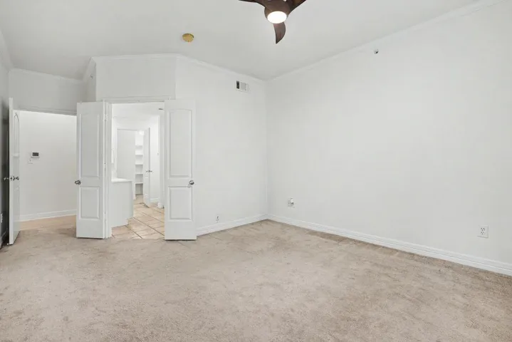 A quiet bedroom retreat with plush carpeting and a modern ceiling fan, offering a serene personal space.