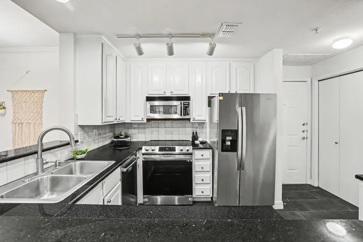 White cabinetry, dark counters, and stainless appliances define this streamlined, modern kitchen.