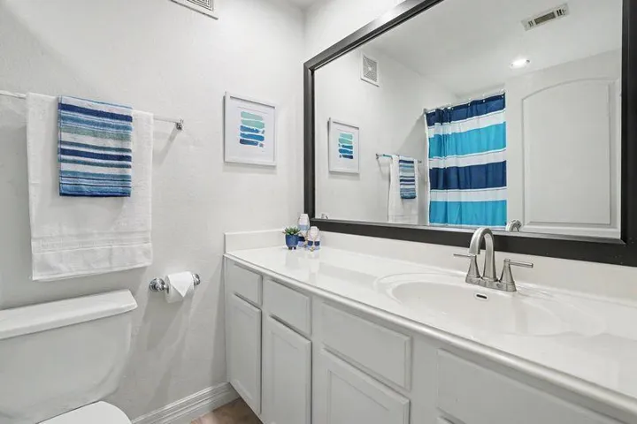 A pristine bathroom features a vanity with ample counter space and a large mirror.