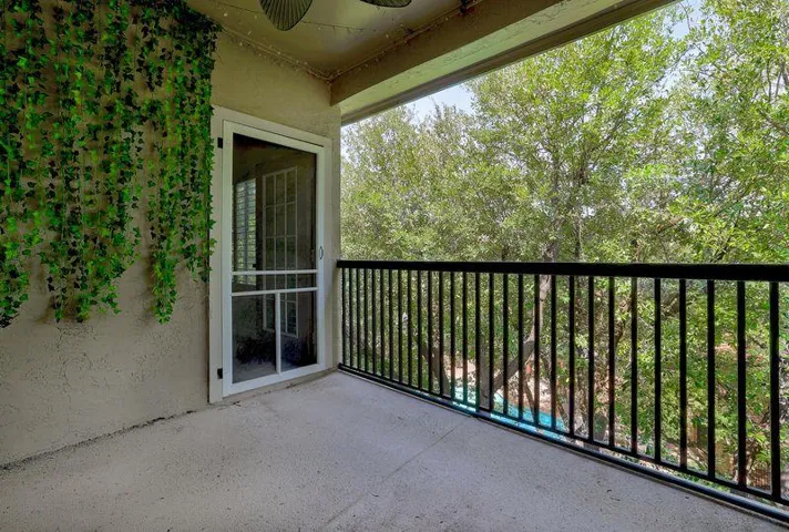 A quiet, covered patio with natural landscaping and a verdant privacy screen awaits outdoor enjoyment.