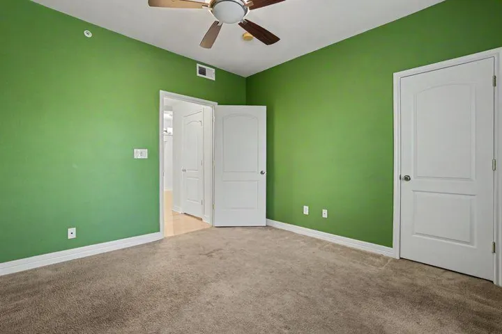 A comfortable bedroom with plush carpeting and a cooling ceiling fan offers a refreshing retreat.