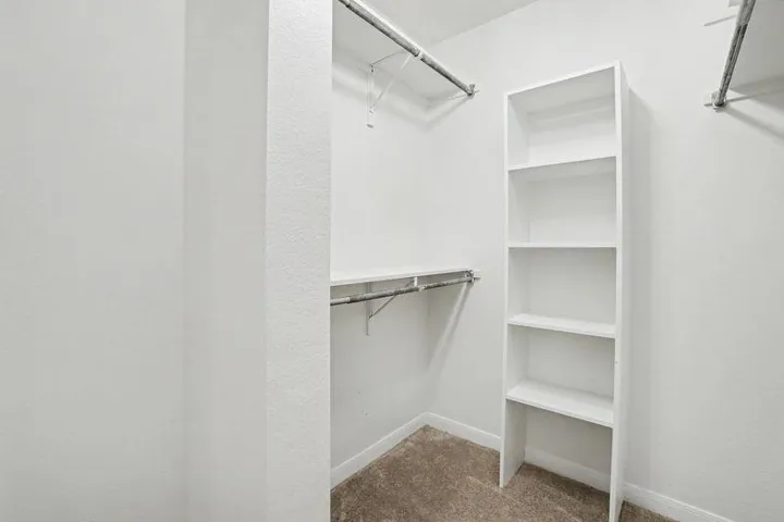 Ample storage solutions abound in this well-organized walk-in closet with built-in shelving.
