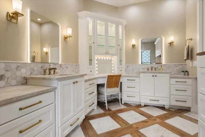 Have you seen a more elegant Primary Bathroom?  Separate dual vanities with counter space for each.  Also lighted mirror for each sink.  Lighted make-up mirror with the makeup vanity & lighted glass front cabinets for your collectibles.  Flooring is marble tile and wood...