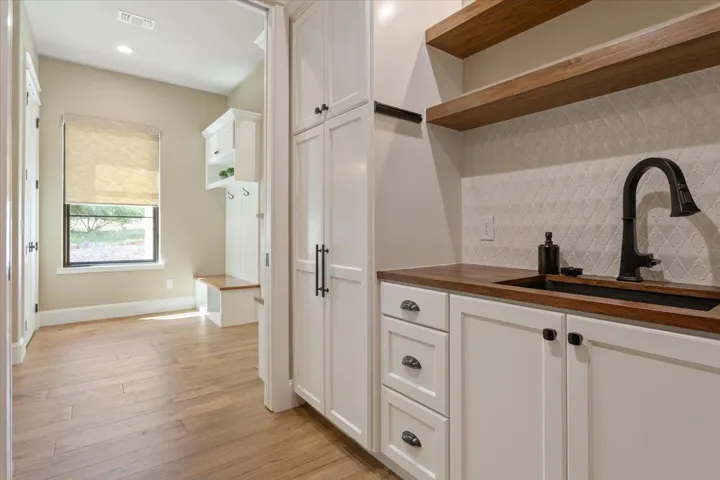 On the right of the Utility Room, another Blanco brand sink with cabinets, drawers, a closet for brooms & vacuums, & floating Walnut shelves...