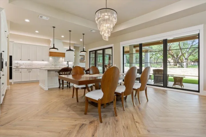 A view from a distance of the dining area with incredible chandelier and a continuation of the wall of windows/doors...