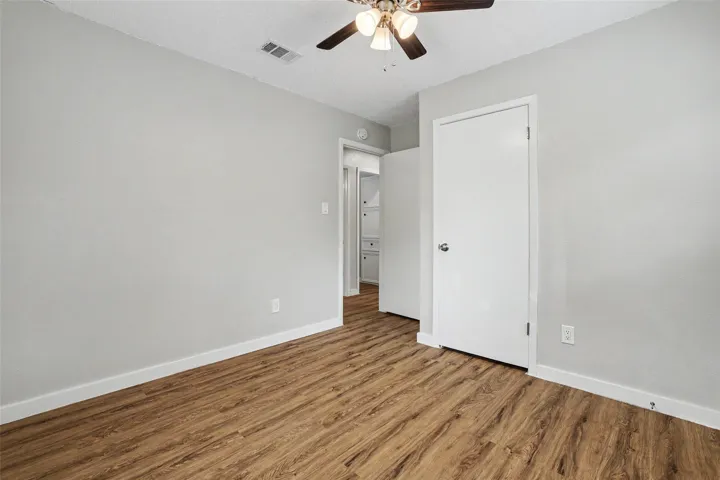 A well-lit bedroom with rich wood flooring offers a comfortable and inviting atmosphere.