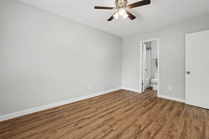 Laminate wood flooring and a refreshing ceiling fan create comfort in this appealing bedroom.