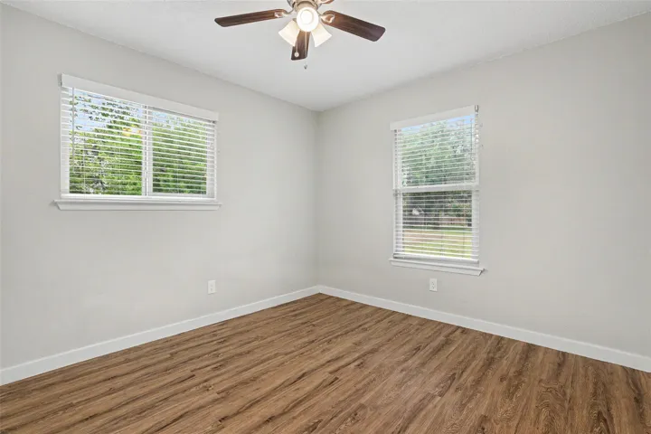 A well-lit bedroom featuring durable plank flooring and a classic ceiling fan.