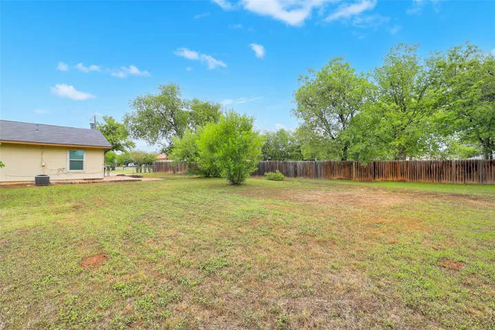 A spacious yard bordered by a wooden fence offers ample room for outdoor activities.