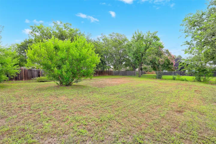 A spacious backyard awaits, fully fenced with mature trees providing natural shade.