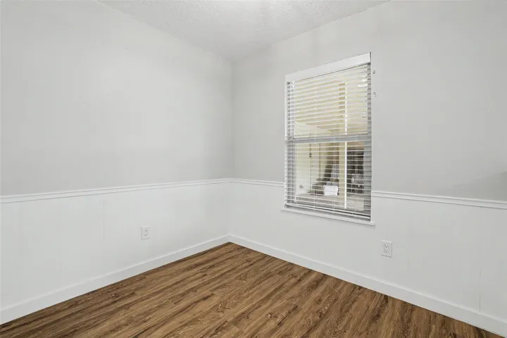 A well-lit room featuring durable wood flooring, ready for personalization.