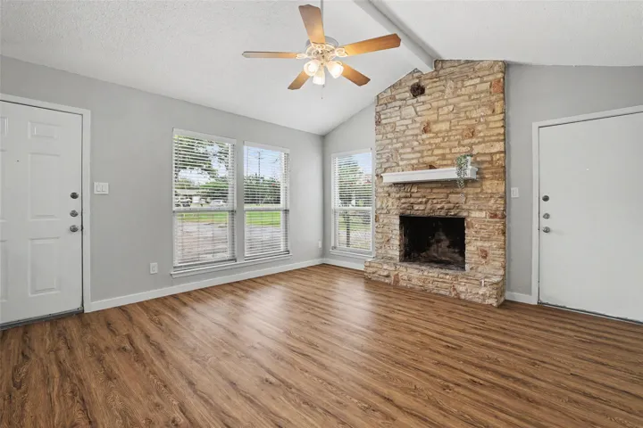 A welcoming living area offers rich wood flooring and a floor-to-ceiling stone fireplace.
