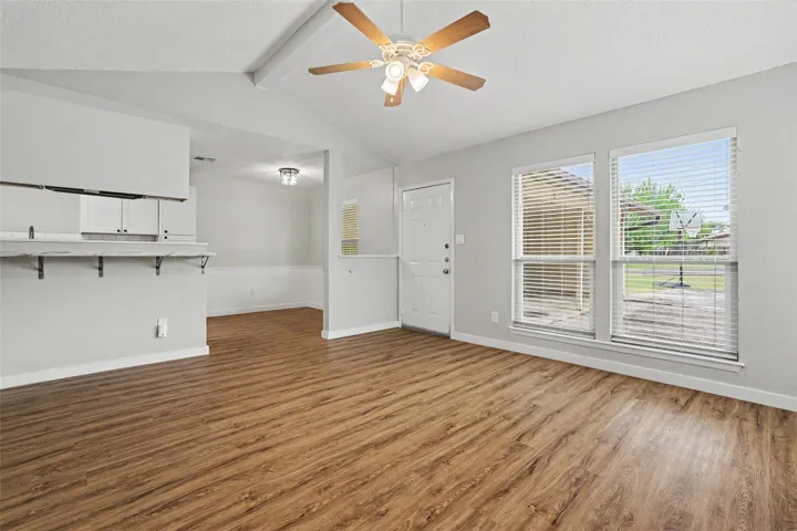A welcoming living space features warm wood flooring and abundant natural light from large windows.