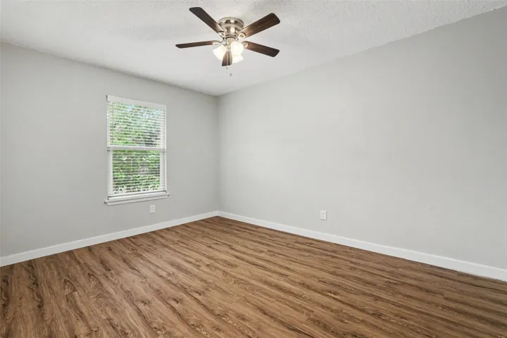 Well-lit room featuring durable laminate flooring and a ceiling fan for year-round comfort.