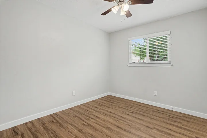 Warm wood-look flooring and a ceiling fan create a comfortable and inviting atmosphere in this bedroom.