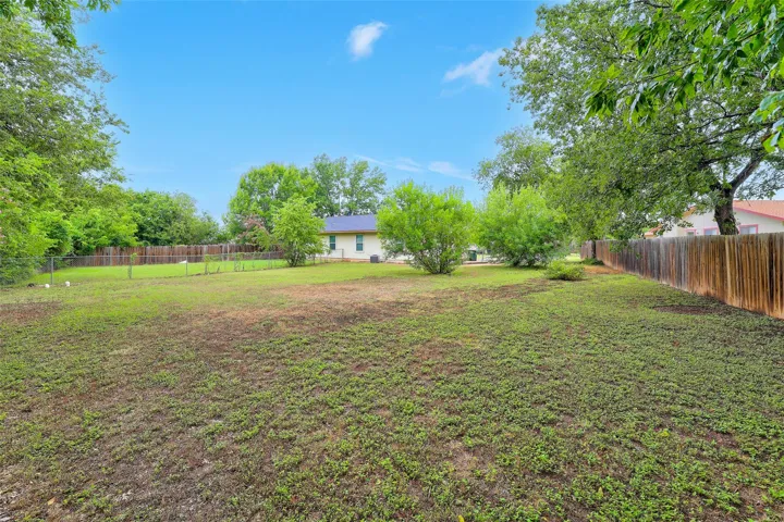 A spacious backyard provides ample green space, bordered by mature trees and a privacy fence.
